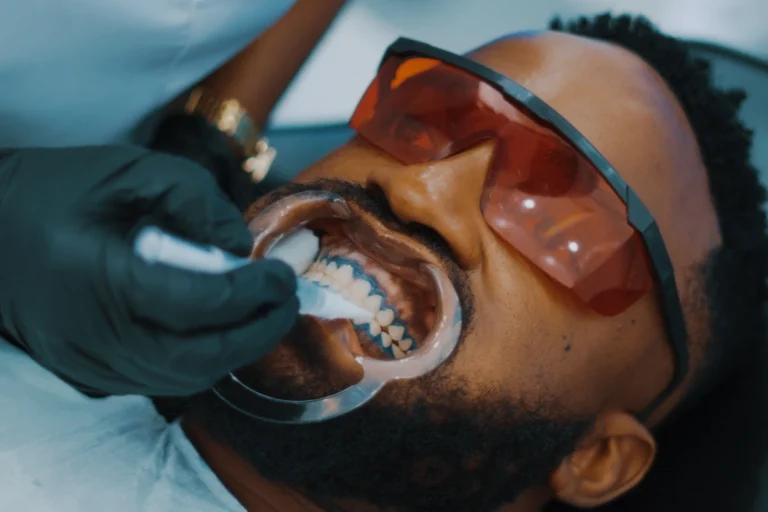 African Nigerian man getting teeth brushed by dentist in Lagos clinic