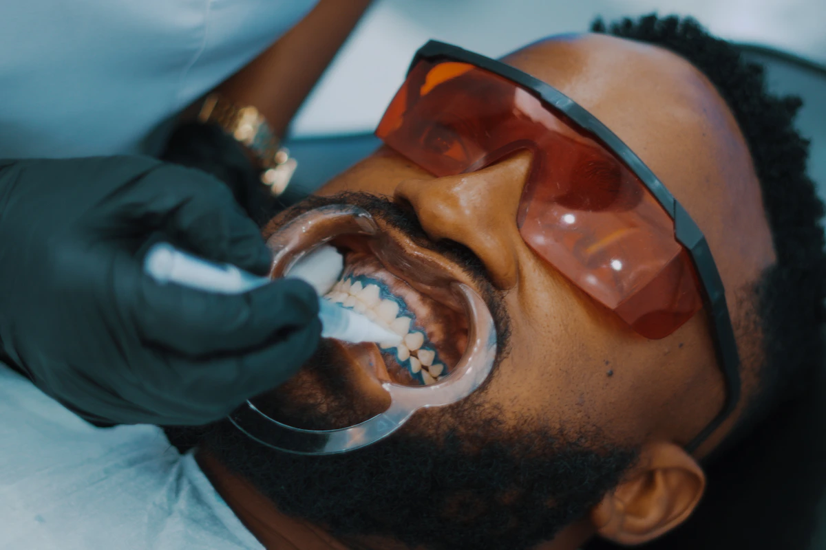African Nigerian man getting teeth brushed by dentist in Lagos clinic